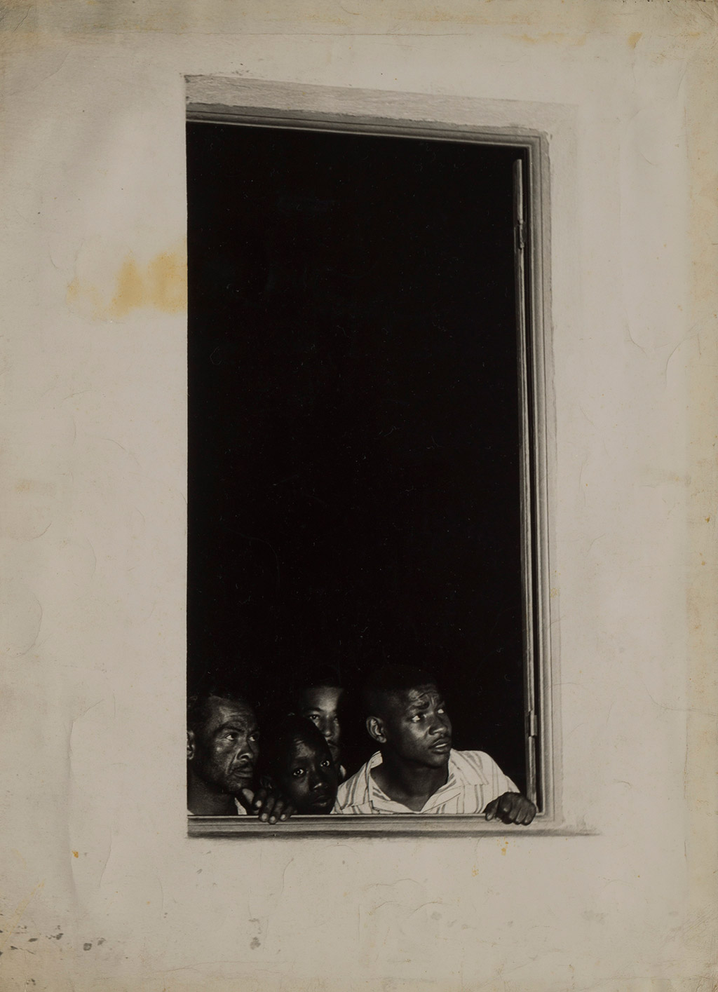 [Description: Black and white photograph of people looking out of a window] 
